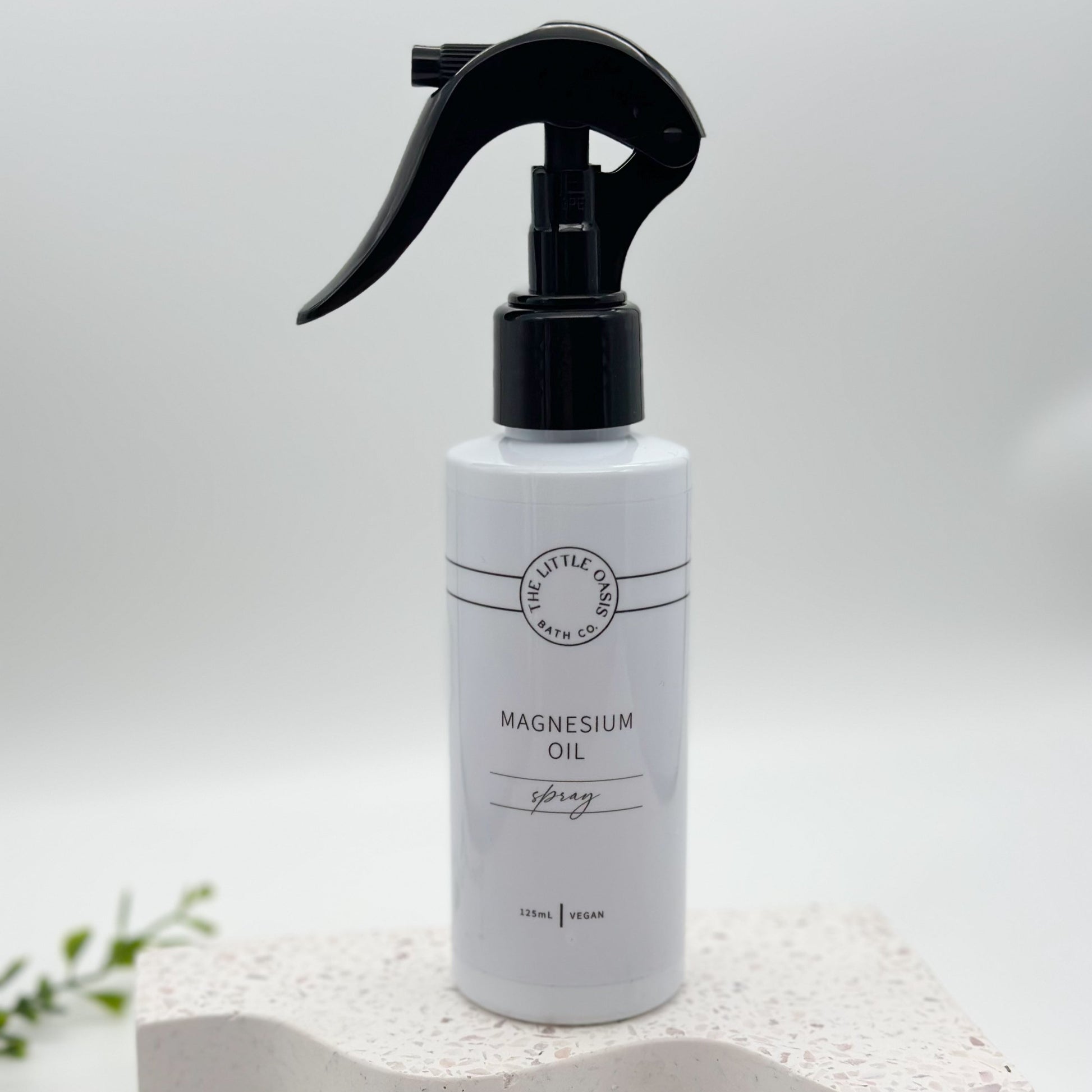 White spray bottle labeled 'Magnesium Oil' on a white background