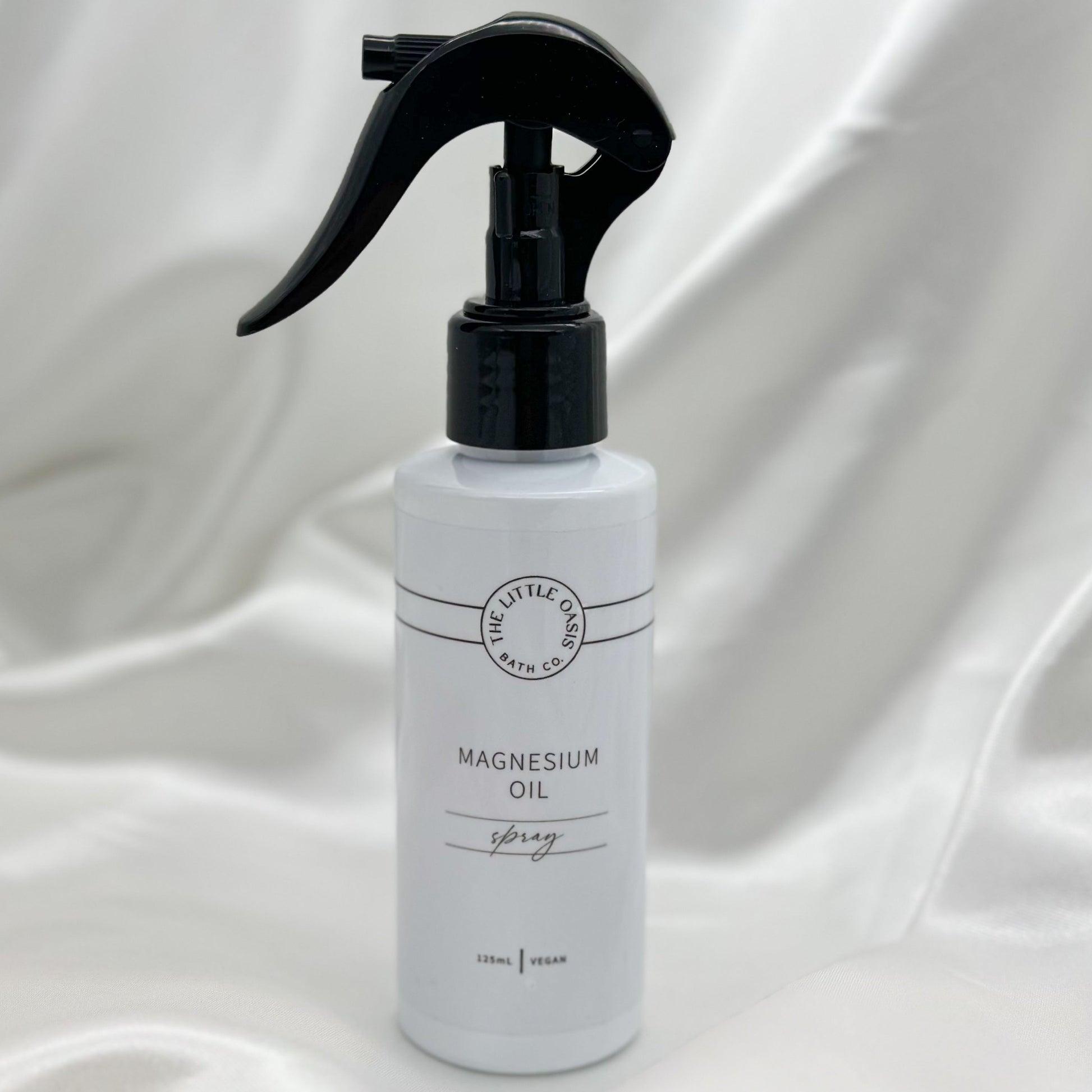 White spray bottle with black nozzle on a white fabric background