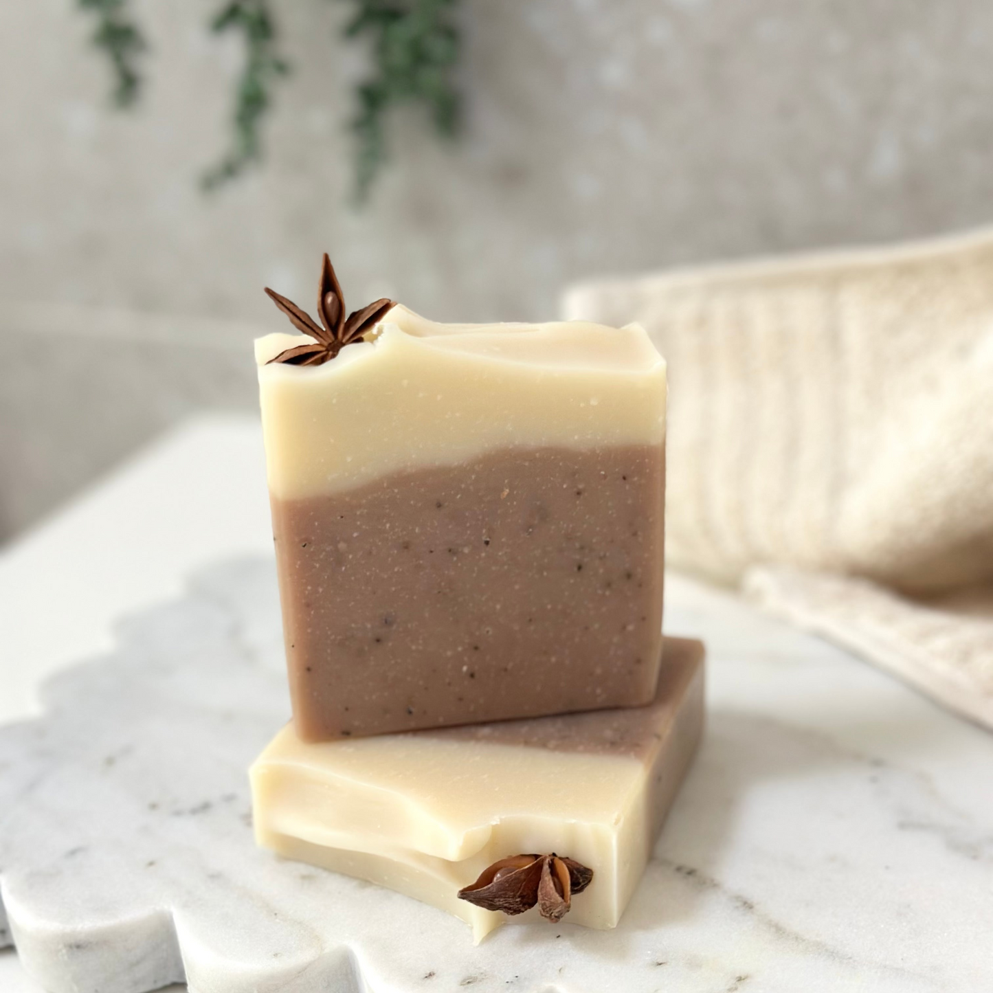 Two stacked soap bars with star anise on a marble surface
